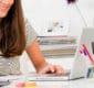 Woman writing and working on laptop computer.